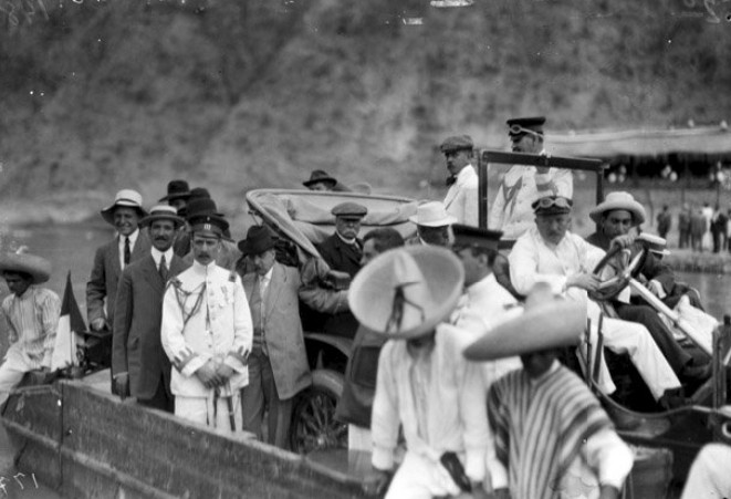 El presidente Díaz a bordo de su automóvil.jpg El presidente Díaz a bordo de su automóvil, transportados ambos -junto con otras personas- sobre una panga para cruzar el río Mezcala en su camino a la inauguración de la carretera Iguala-Chilpancingo. Reproducción autorizada por el INAH.